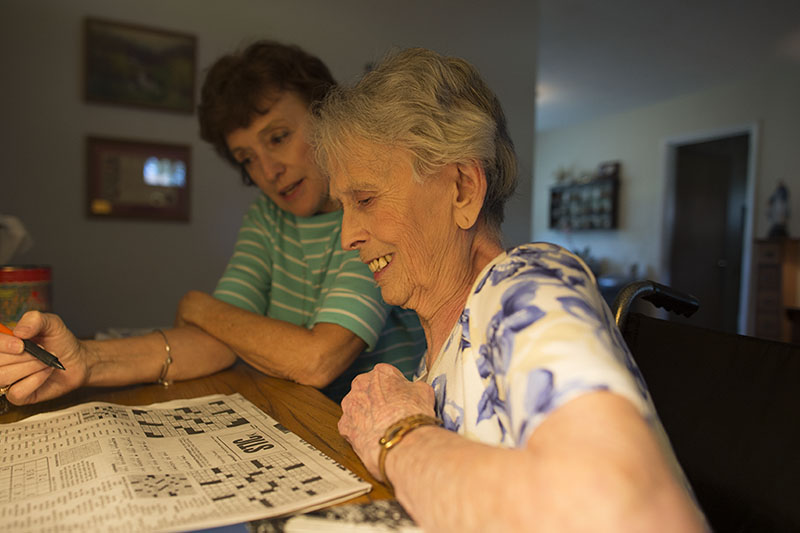 Kathy O'Hara looks on as Kathleen works a crowssword puzzle.