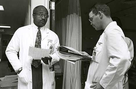 A vintage shot of Dr. Britt discussing charts with a fellow physician